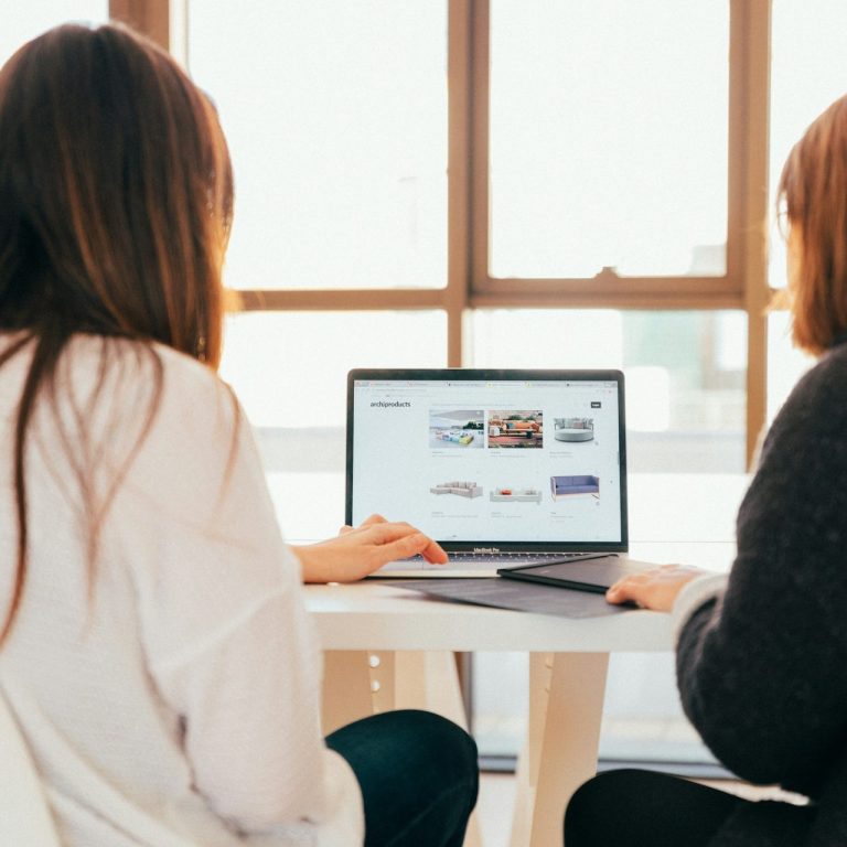 Two people collaborating at a laptop in a bright, modern workspace.